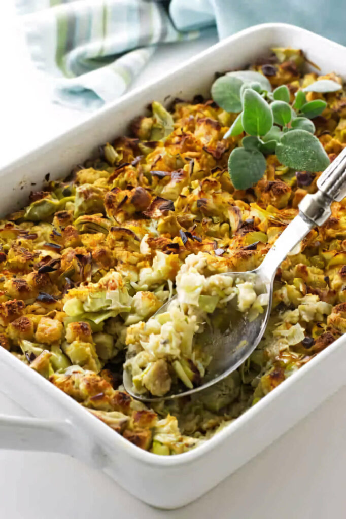 A spoon scooping out a serving of artichoke leek stuffing.