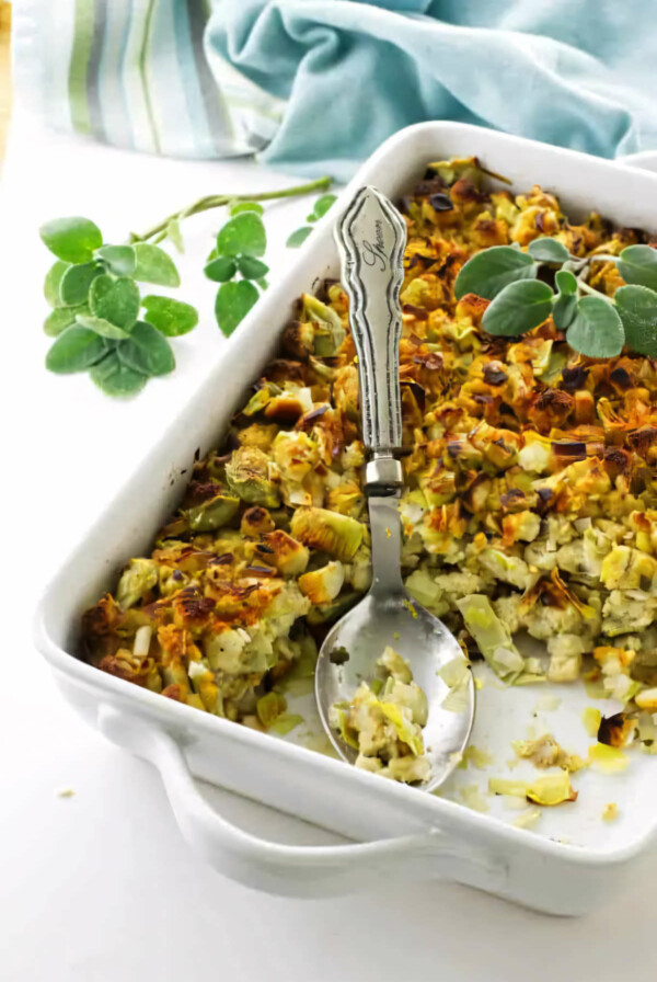 A white casserole dish filled with artichoke and leek stuffing.