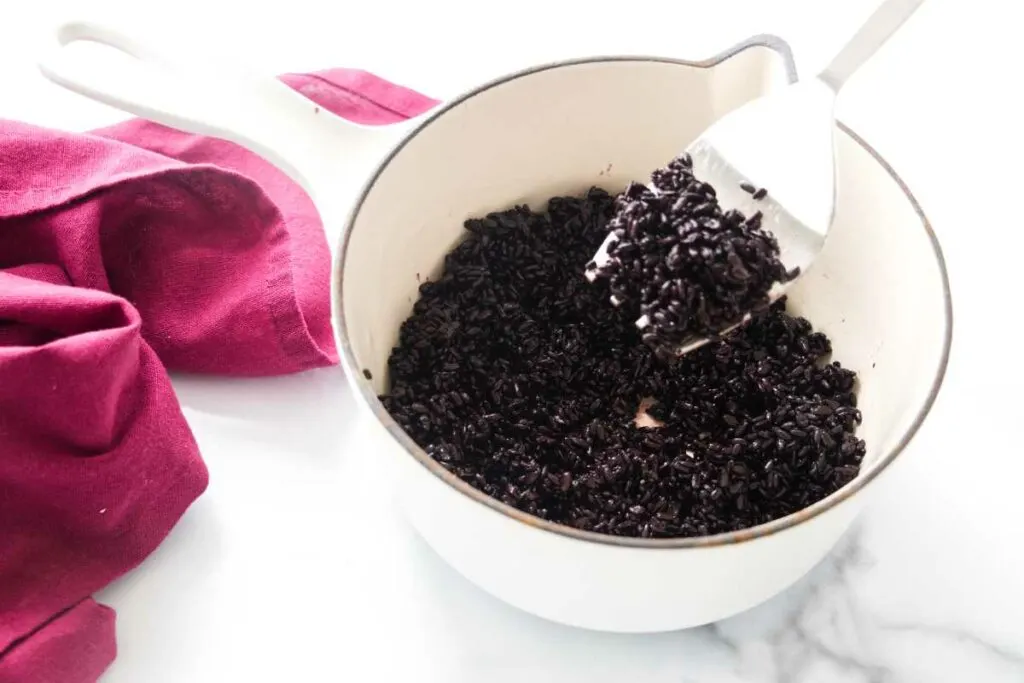 Cooking black rice in a saucepan.