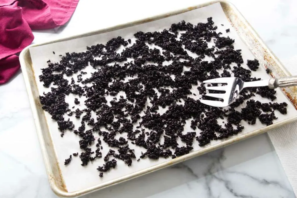 Black rice cooling on a sheet pan.