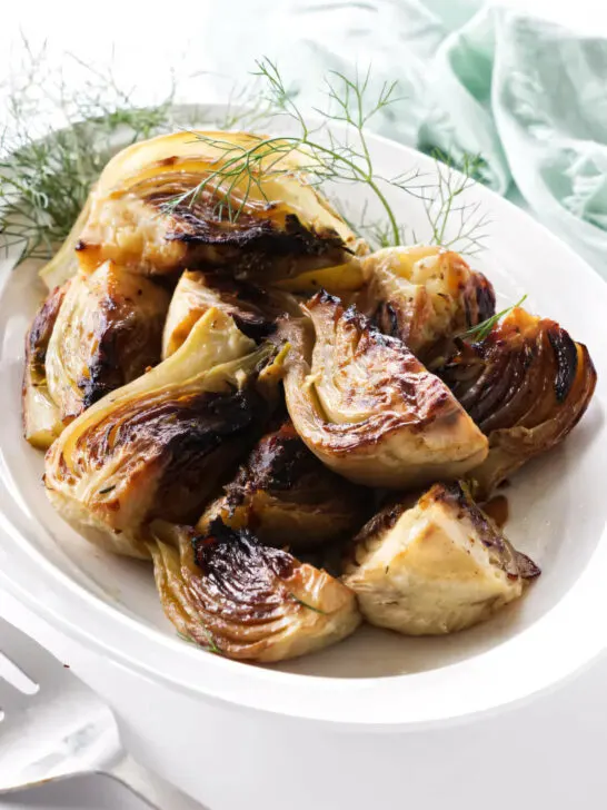 A serving dish with caramelized balsamic fennel next to a serving fork.