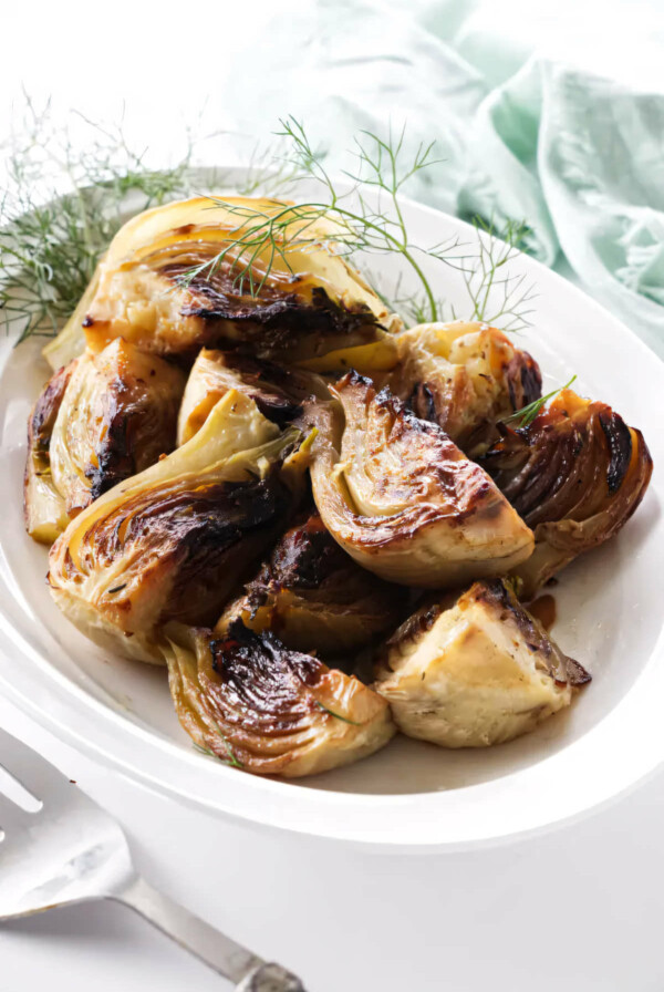 A serving dish with caramelized balsamic fennel next to a serving fork.