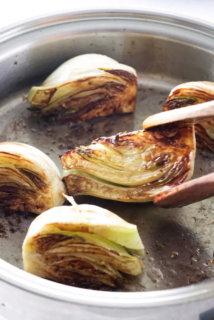 Browning fennel wedges in a skillet.