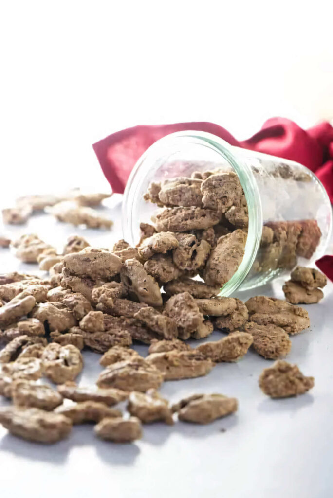 Cinnamon sugar pecans on a white counter with a red napkin in the background.