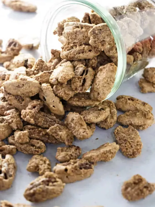 A jar on its side spilling out candied pecans on the counter.