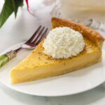 A slice of eggnog tart on a plate with a dollop of whipped cream.