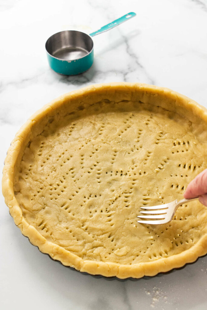 Using a fork to prick air holes in the shortbread dough.