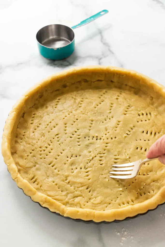 Using a fork to prick air holes in the shortbread dough.