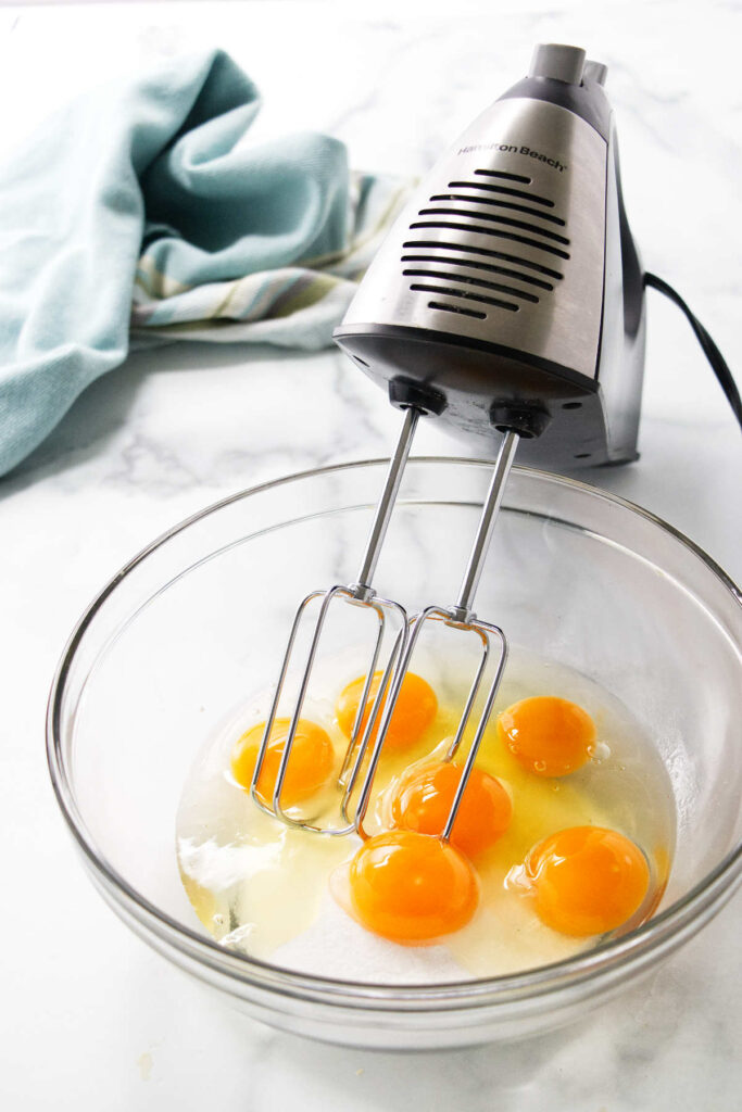 Beating the eggs with sugar in a mixing bowl.