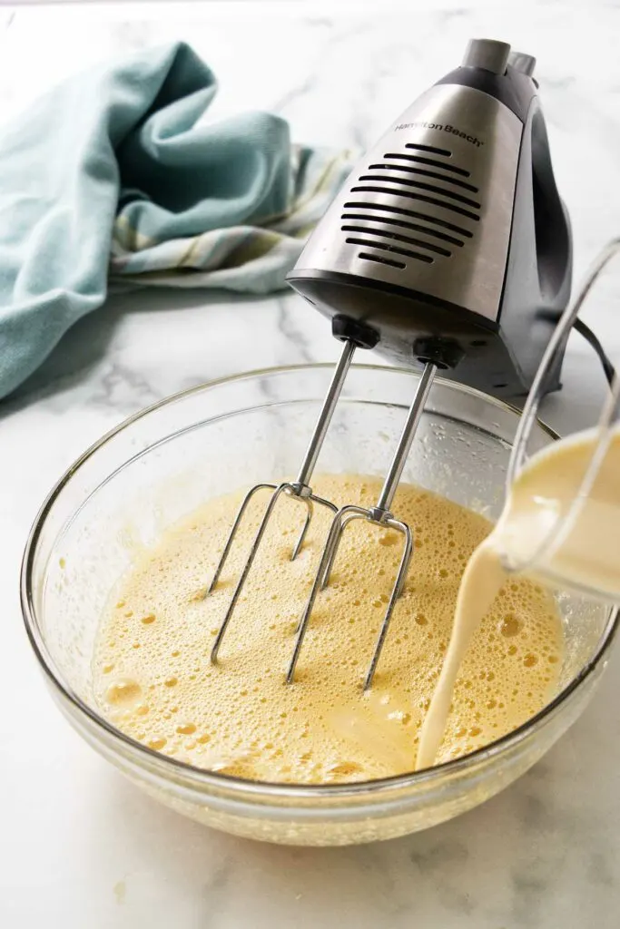 Pouring eggnog into the custard mixture.