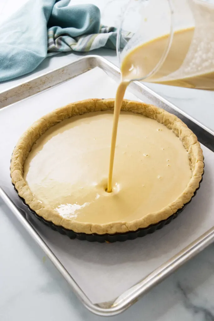 Pouring the eggnog custard into the par baked crust.