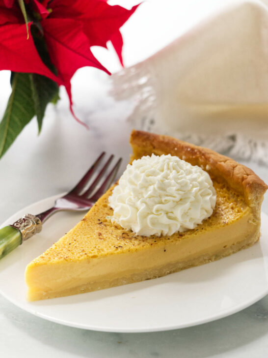 A slice of an eggnog tart next to a poinsettia.