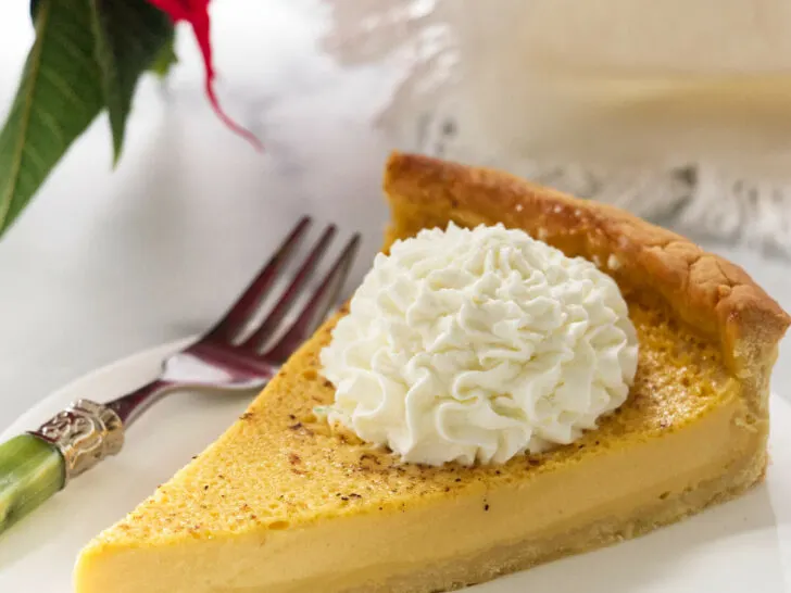 A slice of an eggnog tart next to a poinsettia.