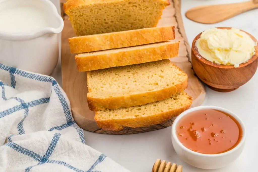 Einkorn sandwich bread slices next to some butter and honey.