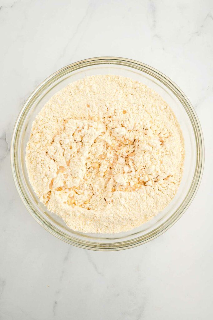 Adding the liquid ingredients to the bowl with einkorn flour to make einkorn yeast bread.