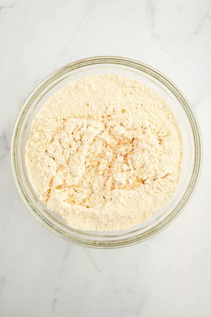 Adding the liquid ingredients to the bowl with einkorn flour to make einkorn yeast bread.