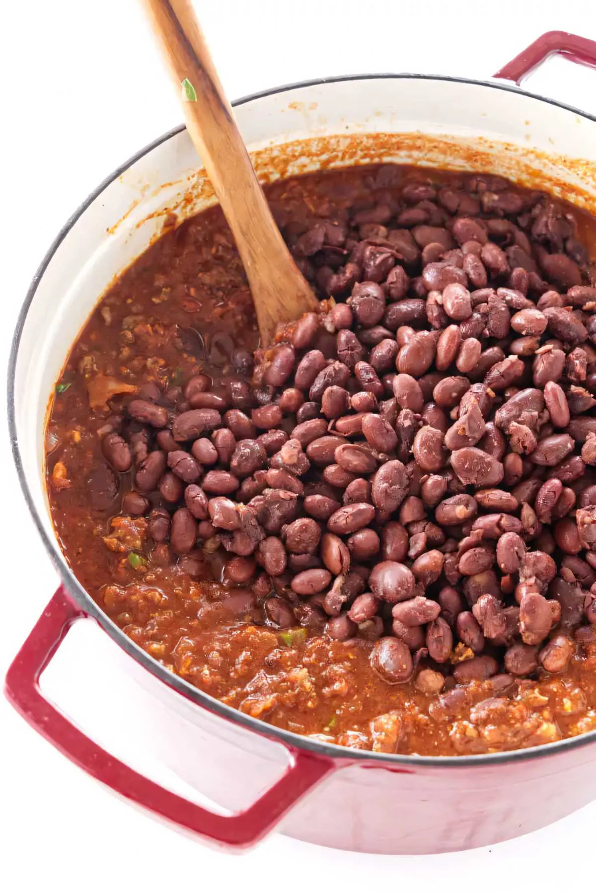 Stirring red beans into a pot of chili.