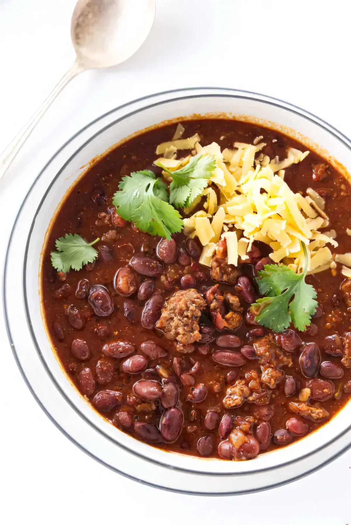 A bowl filled with beef chili beans next to a spoon.