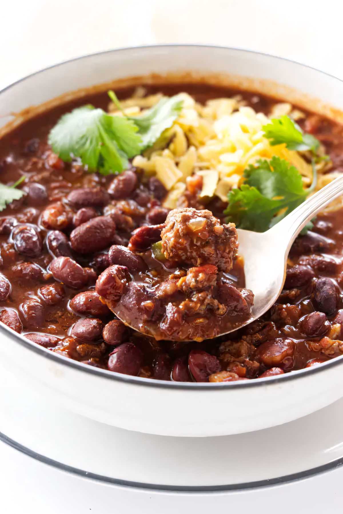 A spoon scooping a serving of chili beans from a bowl.