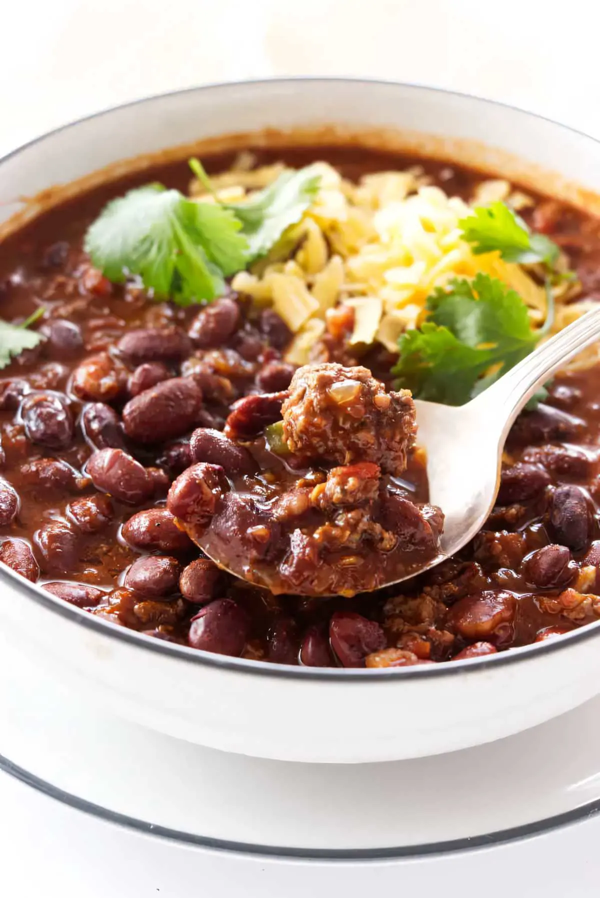 A spoon scooping a serving of chili beans from a bowl.