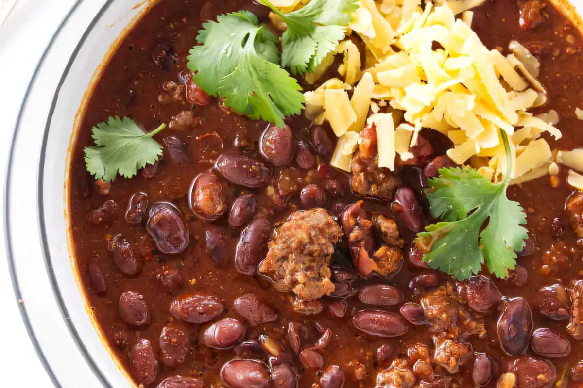 A bowl of chili beans topped with shredded cheese.