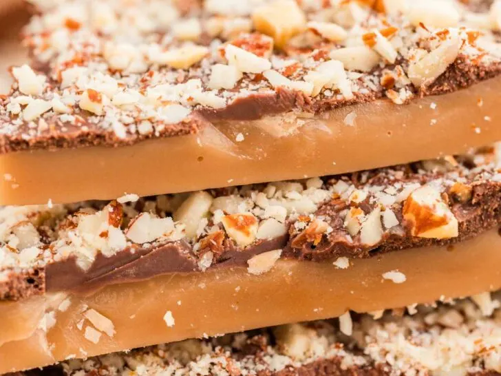 A stack of old fashioned toffee candies topped with toasted almonds.