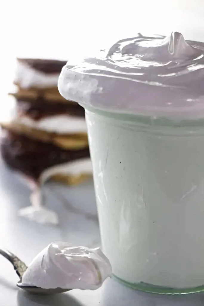 A spoon next to a jar of marshmallow cream.