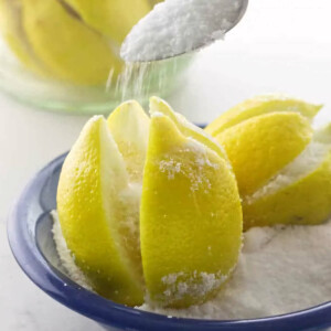 Sprinkling salt over lemons to preserve them.