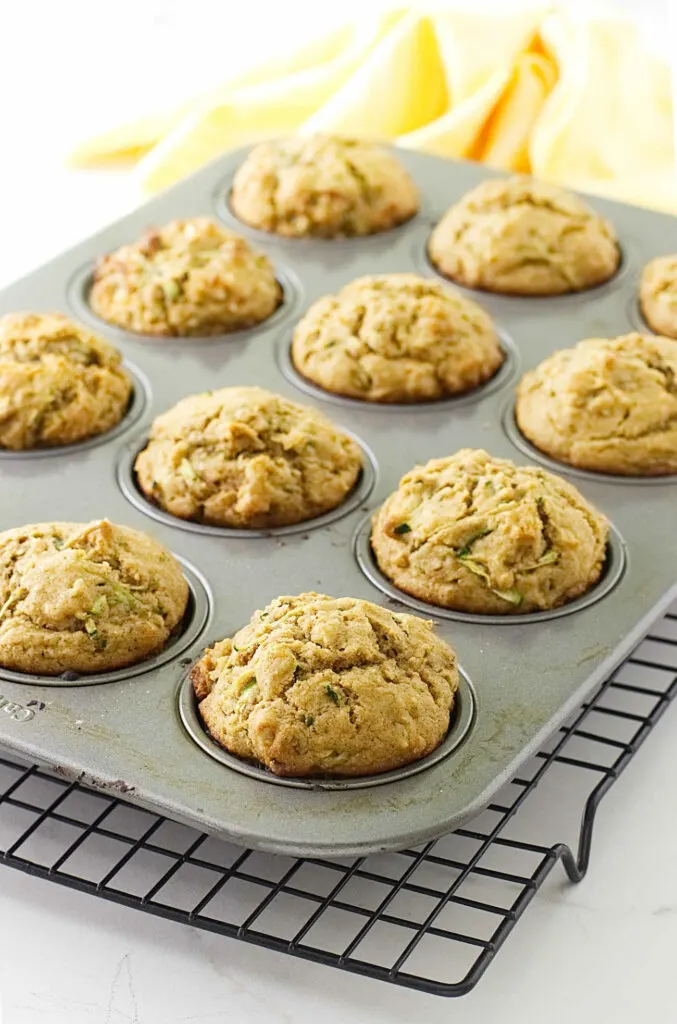 A muffin pan with warm muffins on a cooling rack.