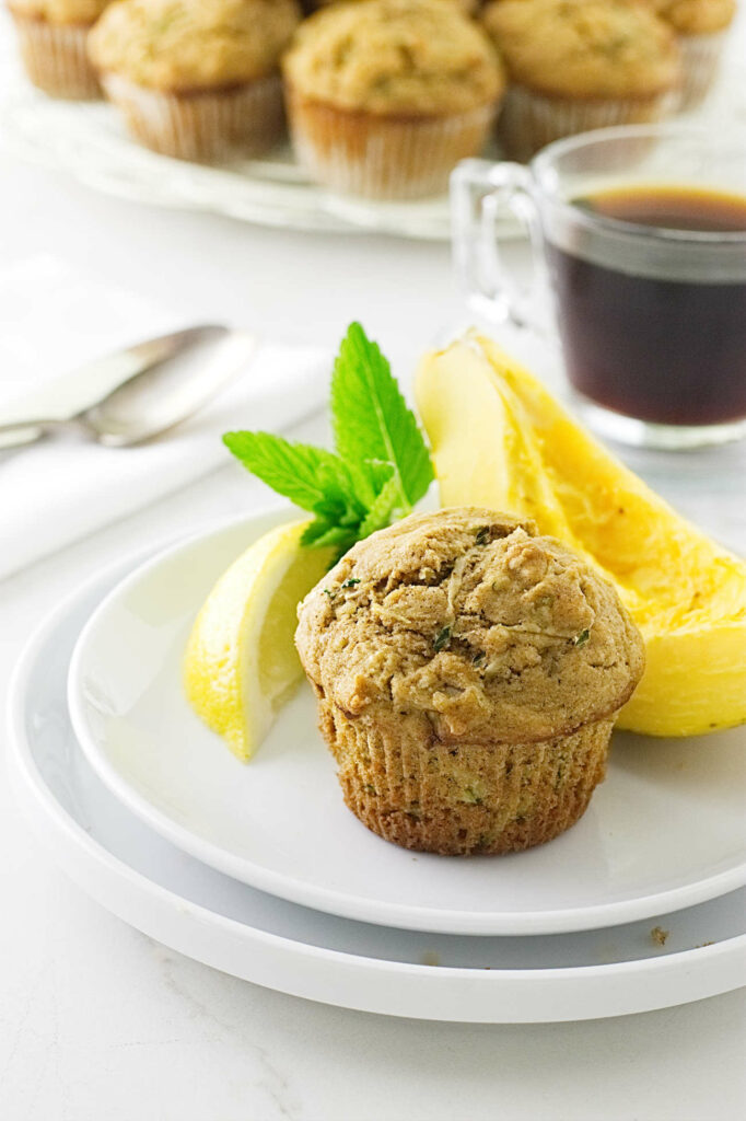 A kamut flourmuffin on a plate with a slice of papaya.