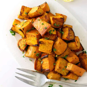 A serving platter filled with chunks of roasted sweet potatoes.