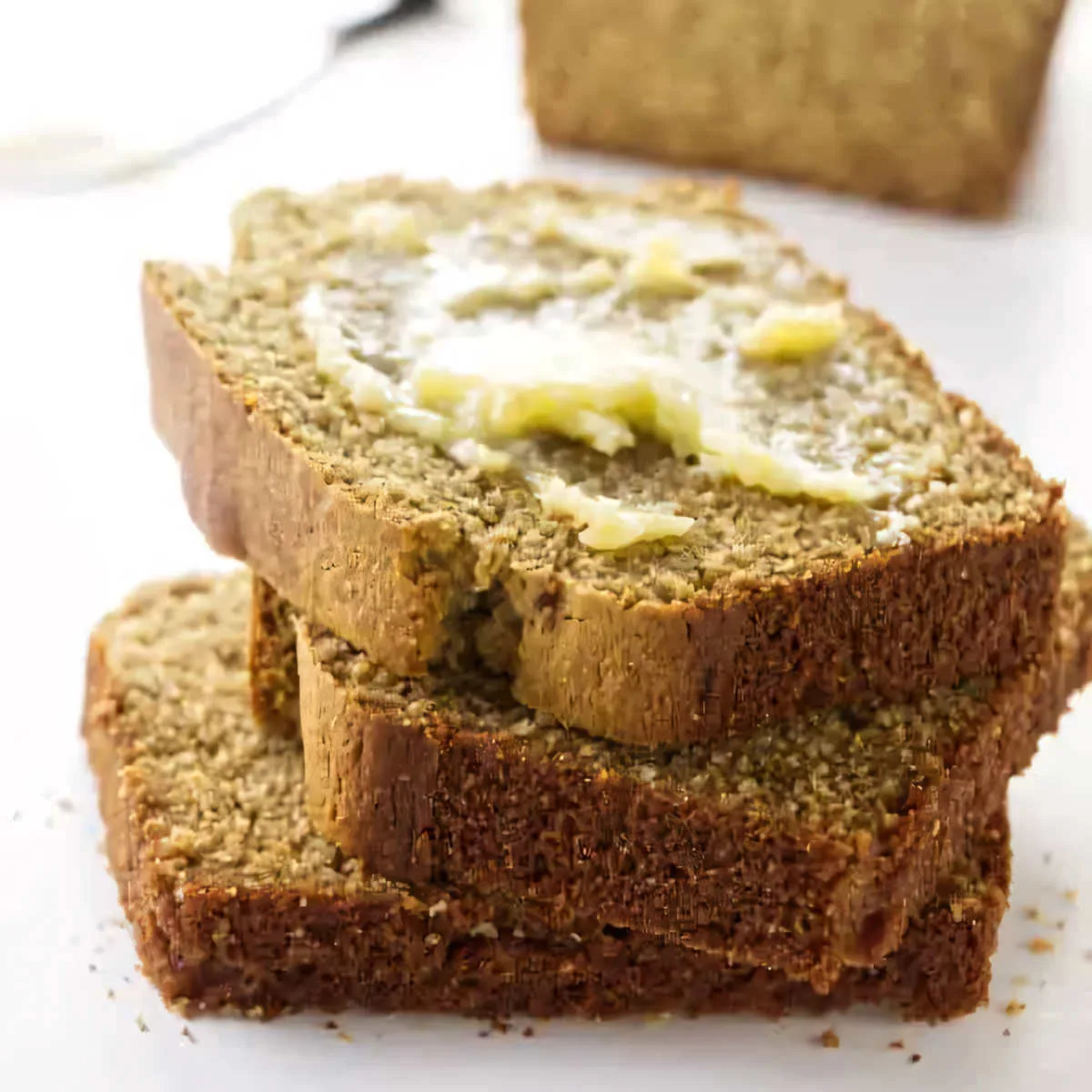 Three slices of barley quick bread topped with butter.