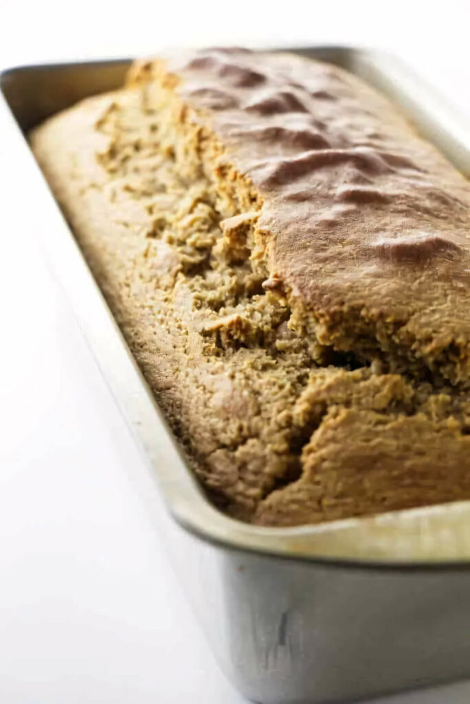 Freshly baked barley bread cooling in a loaf pan.