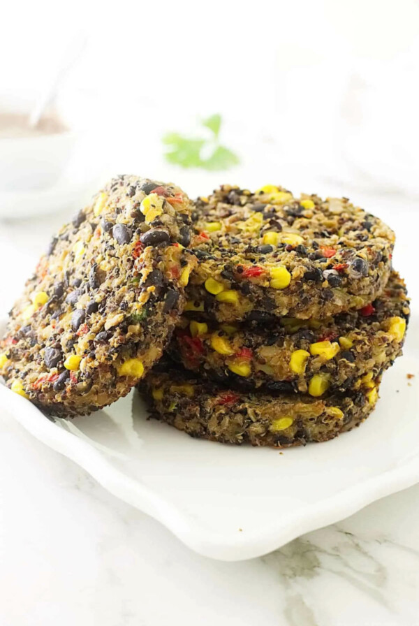 A stack of quinoa and black bean burger patties on a white plate.