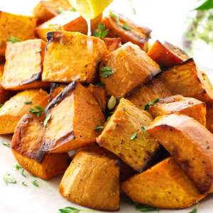 Squeezing a lemon over a cubes of roasted sweet potatoes.