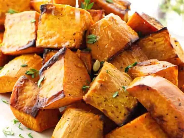 Squeezing a lemon over a cubes of roasted sweet potatoes.