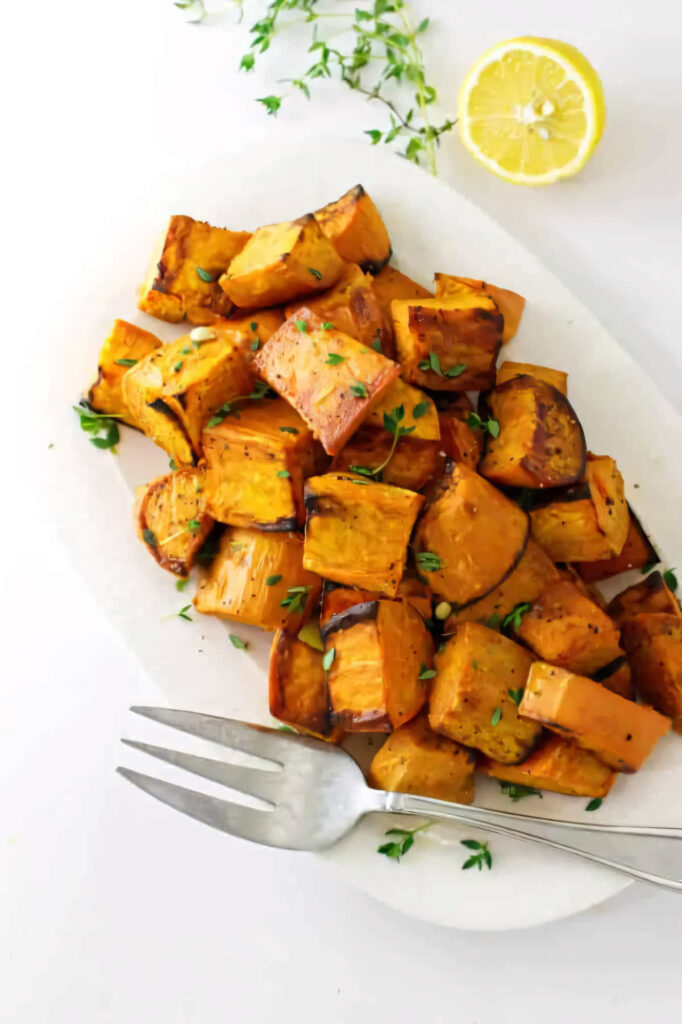 A fork on a serving platter filled with diced roasted sweet potatoes.