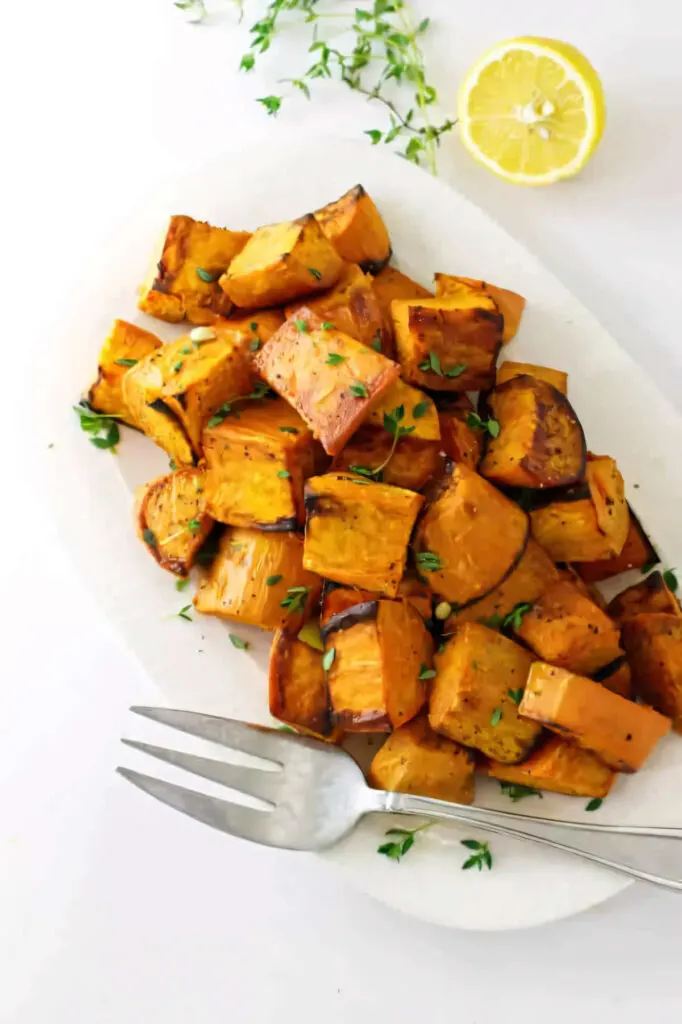 A fork on a serving platter filled with diced roasted sweet potatoes.