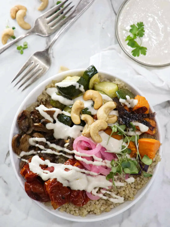 Roasted vegetables and pickles on top of a bowl of quinoa.