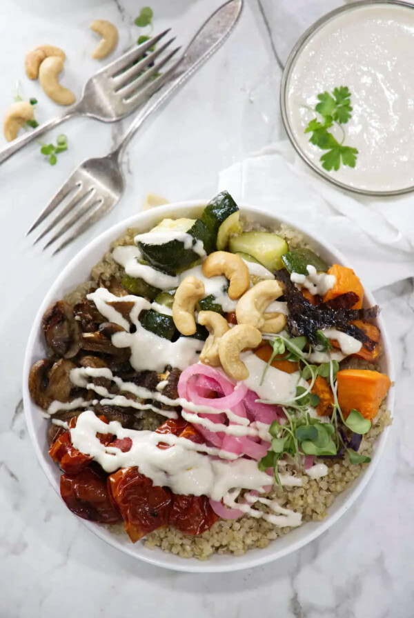 Roasted vegetables and pickles on top of a bowl of quinoa.