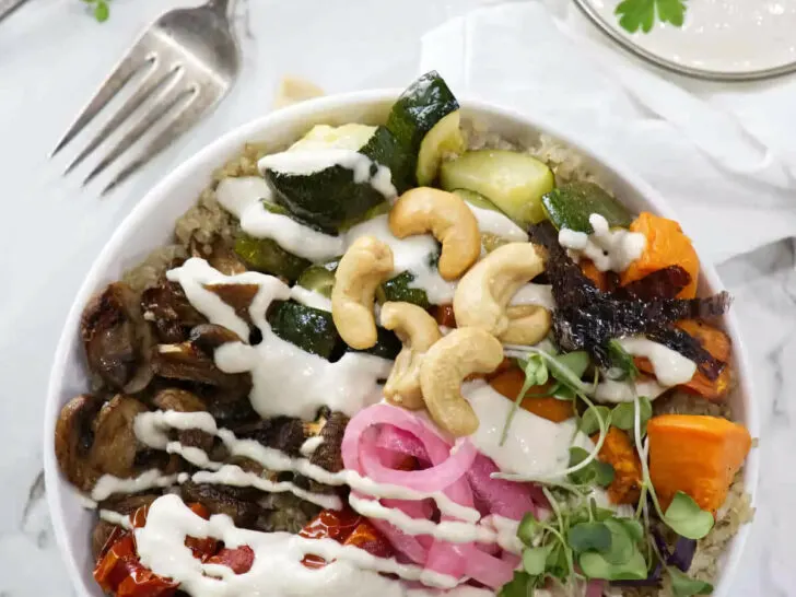 Roasted vegetables and pickles on top of a bowl of quinoa.