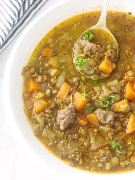 A bowl filled with a serving of sausage lentil soup.