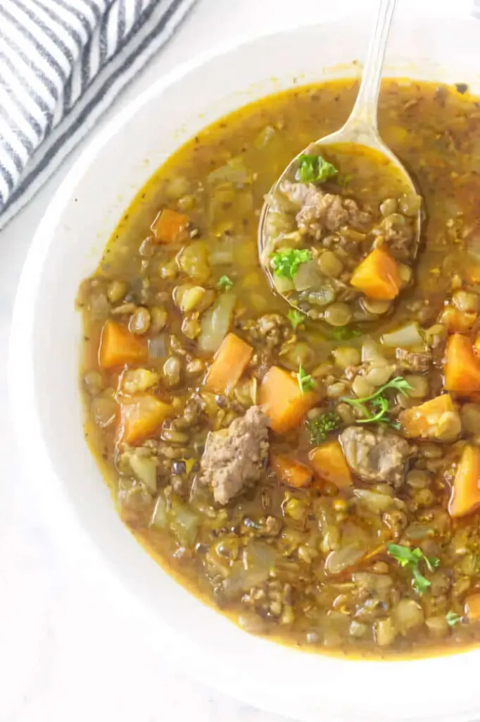 A bowl filled with a serving of sausage lentil soup.