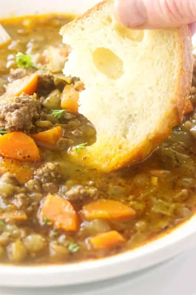 Dipping bread in a bowl of lentil and sausage soup.