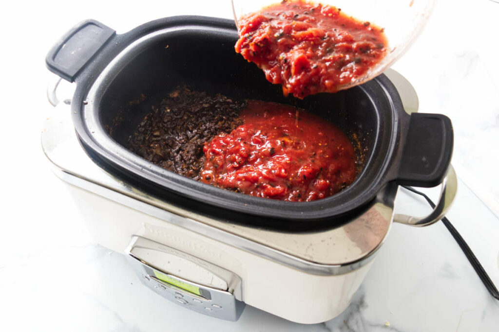 Pouring tomato sauce into the crockpot.