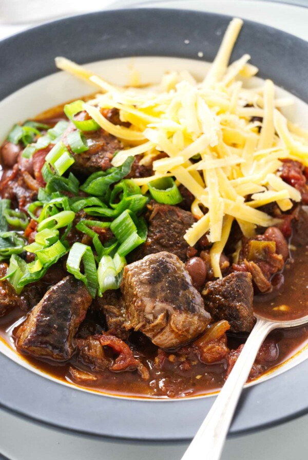 A spoon in a bowl of beef chili with beans.