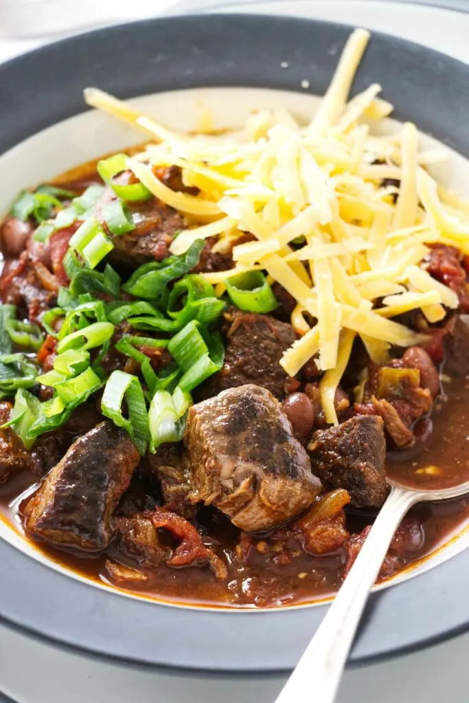 A spoon in a bowl of beef chili with beans.