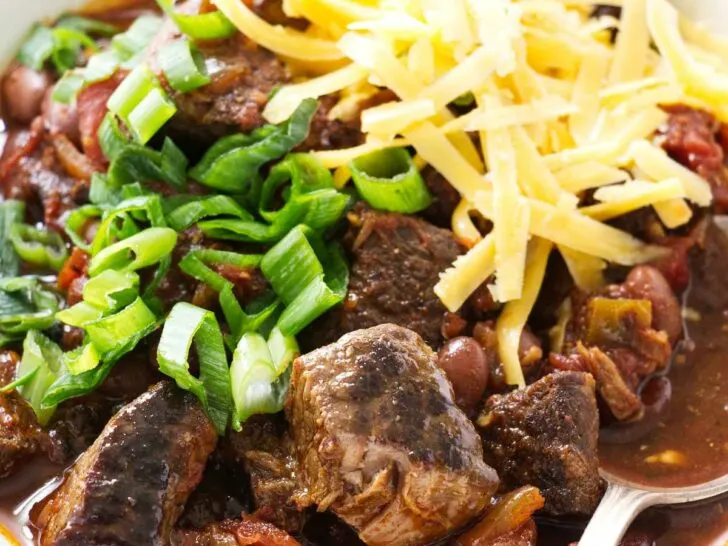 A spoon in a bowl of beef chili with beans.