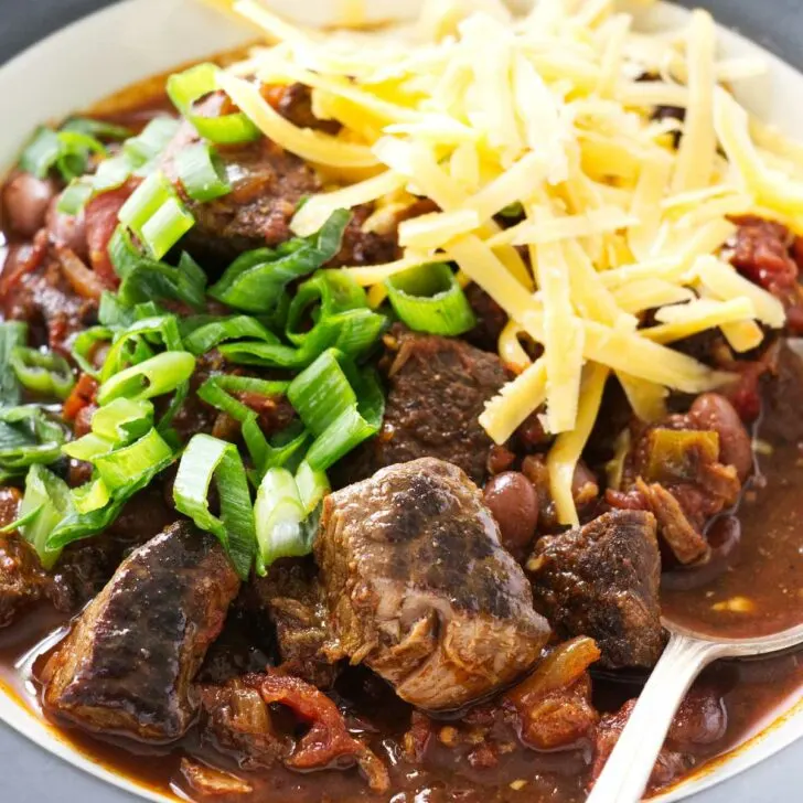 A spoon in a bowl of beef chili with beans.