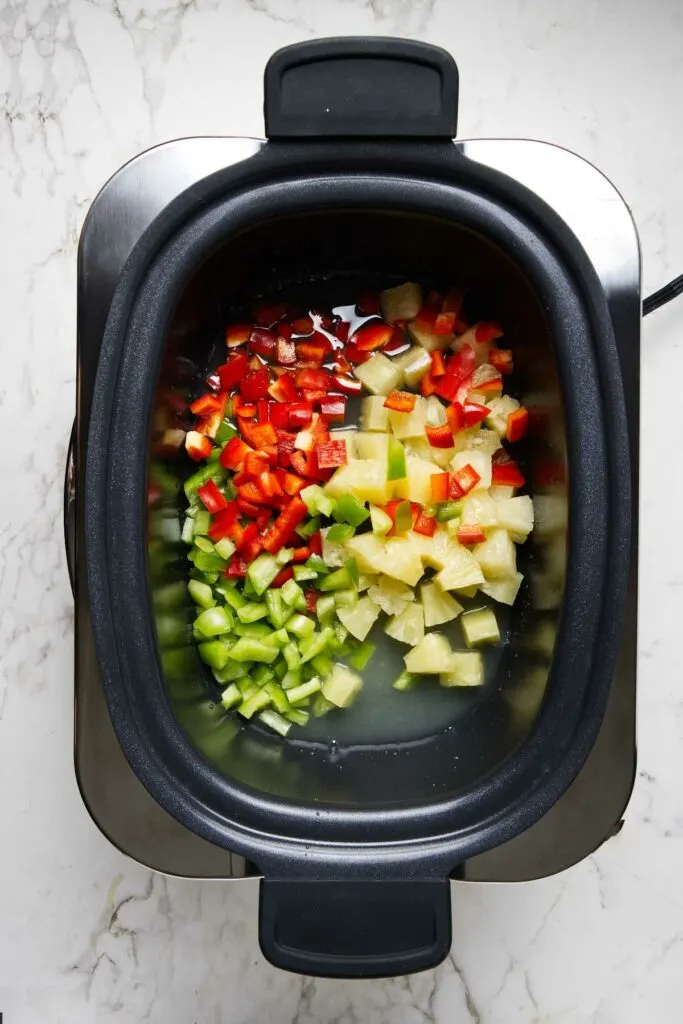 Tossing bell pepper chunks into the slow cooker.